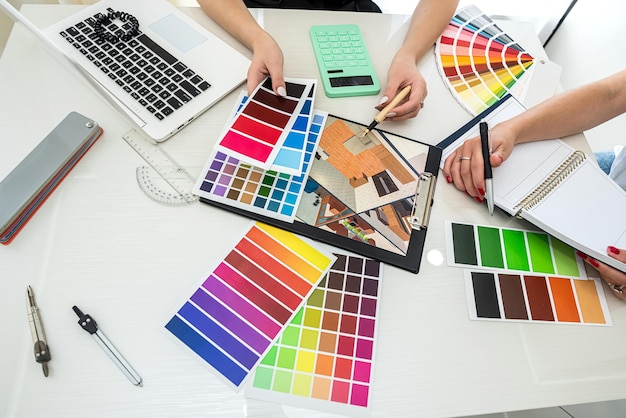 Foto lindas mãos jovens escolhem na paleta de cores em projetos com laptop na mesa conceito de design