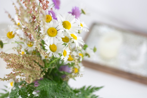 Lindas margaridas e outras flores em uma mesa branca.