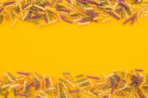 Lindas massas italianas não cozidas e coloridas de farfalle fechadas na vista horizontal de fundo amarelo