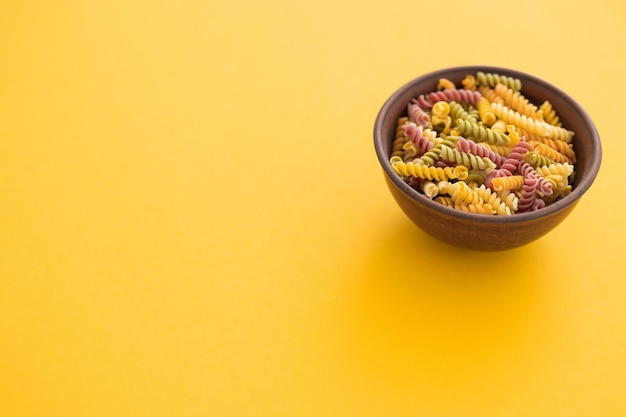 Lindas massas italianas não cozidas e coloridas de farfalle fechadas na vista horizontal de fundo amarelo