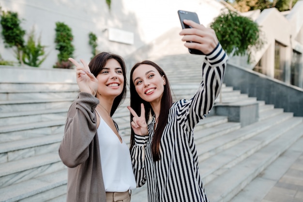 Lindas mulheres casuais fazendo selfie ao ar livre na cidade