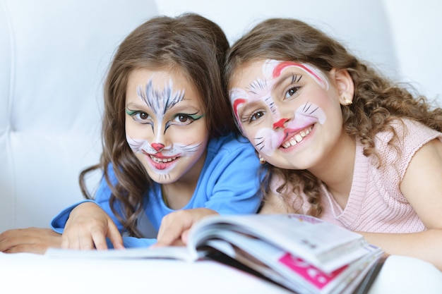 Lindas niñas con cara pintada y revista.