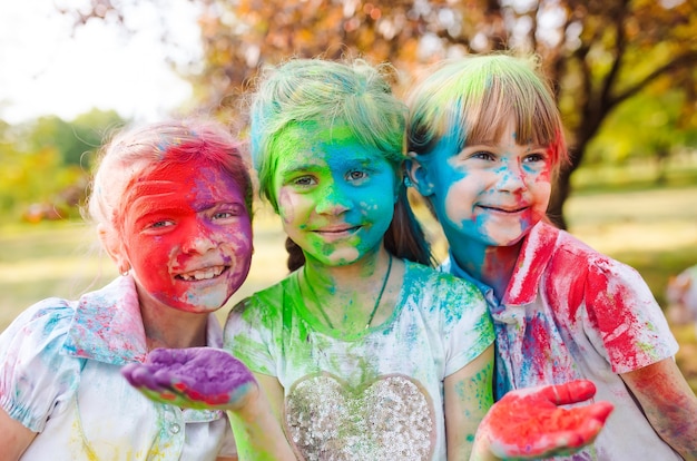 Lindas niñas europeas celebran el festival holi indio con pintura en polvo de colores en las caras y el cuerpo