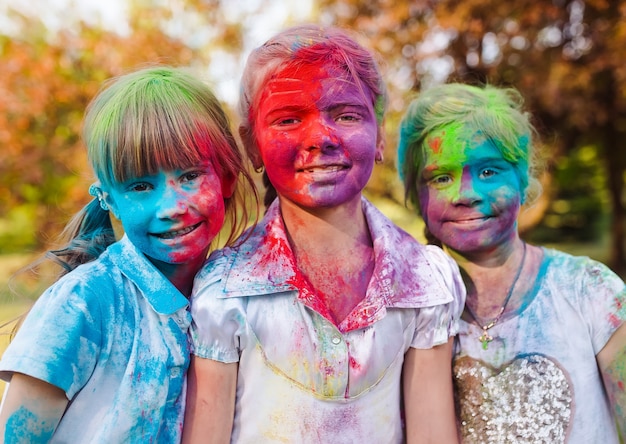 Lindas niñas europeas celebran el festival holi indio con pintura en polvo de colores en las caras y el cuerpo