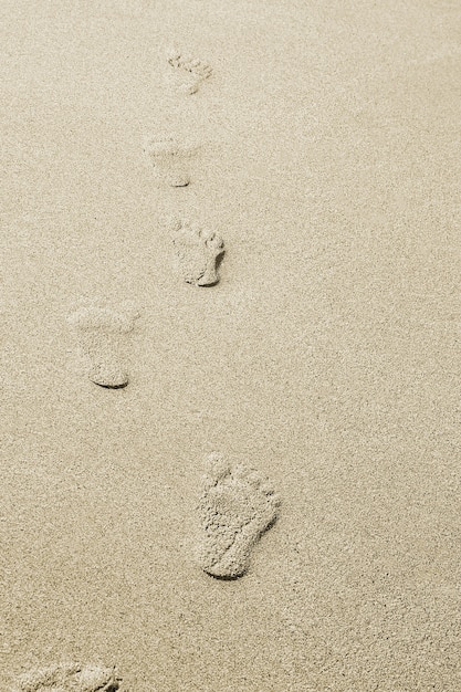 Foto lindas pegadas com pés no fundo de areia