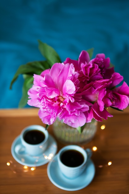 Foto lindas peônias rosa e duas xícaras de café