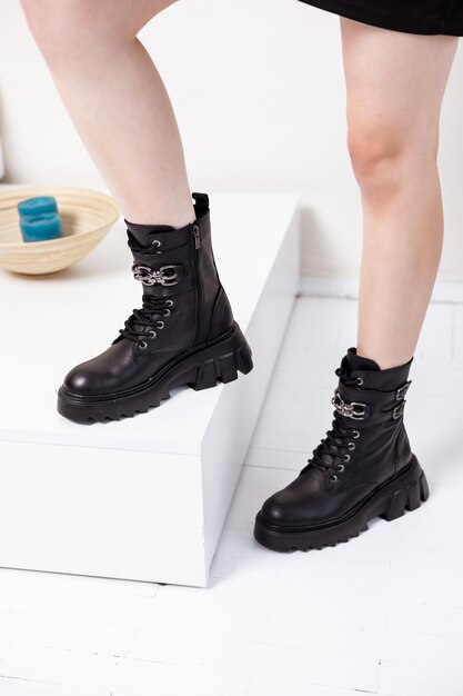 Lindas pernas femininas com elegantes botas pretas no fundo no estúdio. Botas de couro elegantes para mulheres.