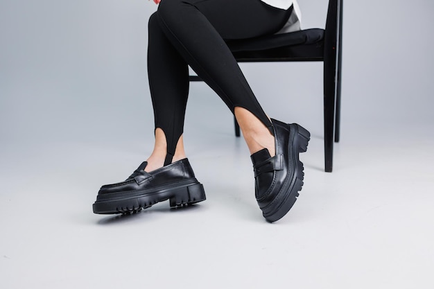 Lindas pernas femininas em mocassins de couro preto e leggings pretas Sapatos femininos de verão