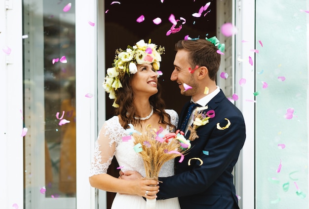 Lindas pétalas de flores caem, abraços de noiva e noivo e sorrindo