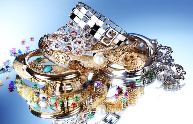 Lindas pulseiras e anéis de prata e ouro sobre fundo azul