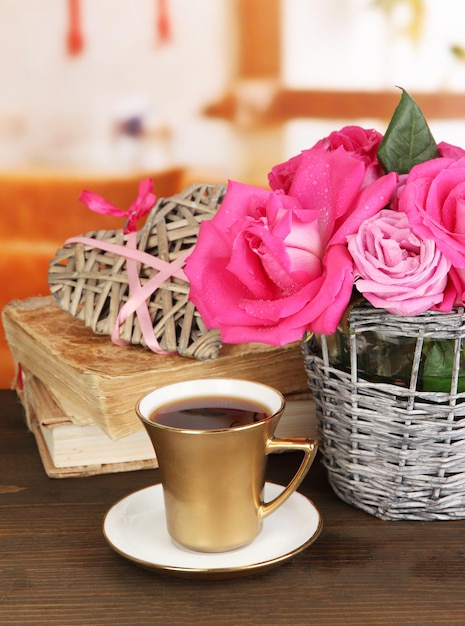 Lindas rosas cor de rosa em um vaso na mesa de madeira no fundo da sala