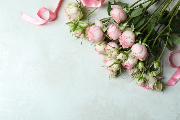 Lindas rosas e fita rosa em plano de fundo texturizado branco