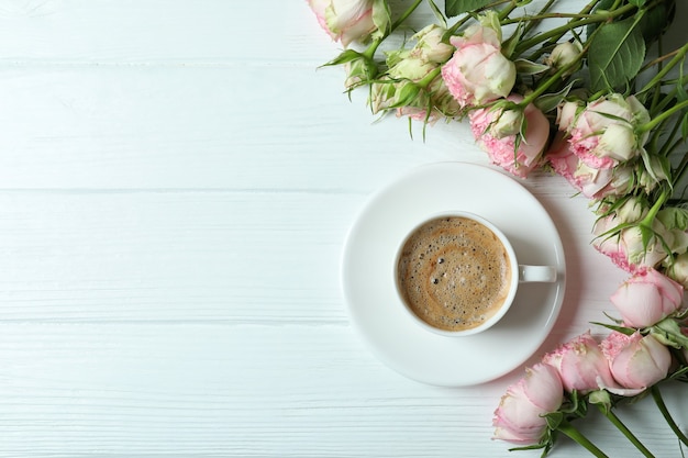 Lindas rosas e uma xícara de café em madeira branca