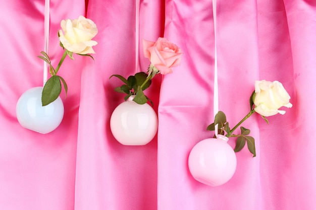 Lindas rosas em vasos pendurados em um fundo de pano