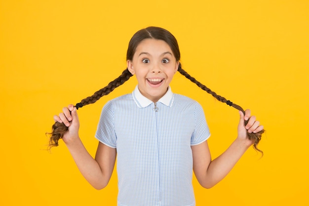 Lindas trenzas Colegiala tierna sobre fondo amarillo Peinado ordenado Niña con lindas trenzas Hermosas trenzas Concepto de peinado trenzado Chica con peinado trenzado Peluquería