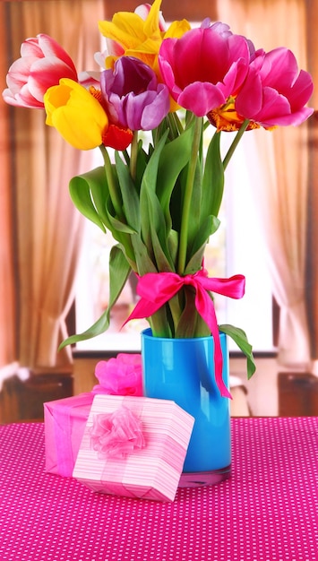 Foto lindas tulipas em buquê com presentes na mesa no quarto