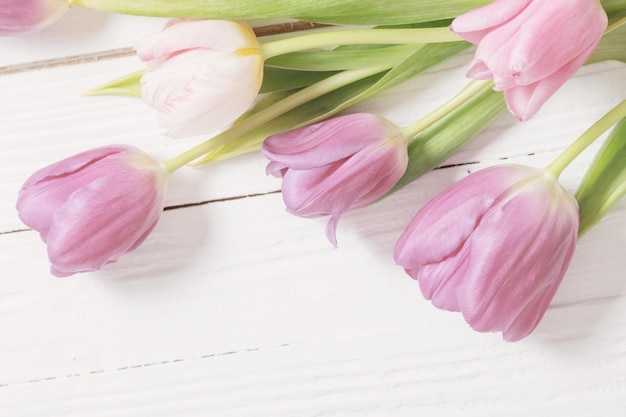 Lindas tulipas em fundo branco de madeira