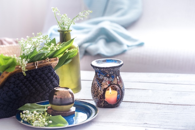 Lindas velas acesas com folhas verdes na bolsa na mesa branca