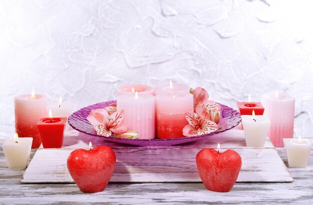 Lindas velas com flores na mesa em fundo cinza