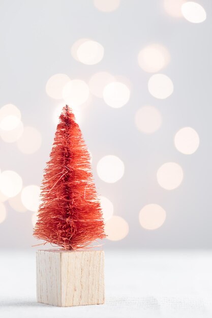 Lindo abeto en miniatura de Navidad en una mesa blanca con luces bokeh