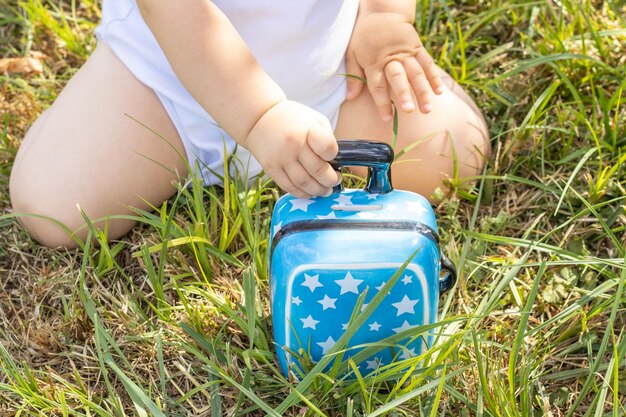 lindo adorable bebé jugando con una pequeña maleta azul para ahorrar monedas, dinero, alcancía. turismo, viaje,