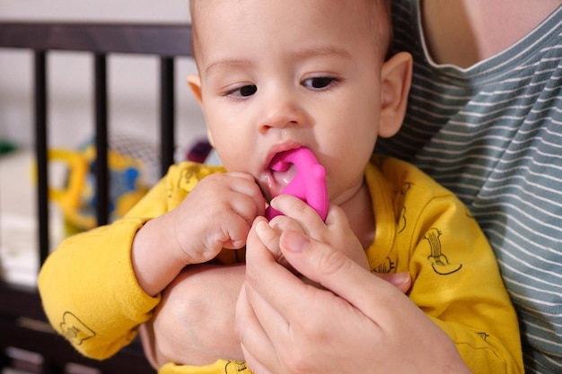 Lindo adorable bebé recién nacido jugando con colorido juguete sonajero bebé con mordedor retrato de bebé encantador de seis meses en blanco con juguete mordedor