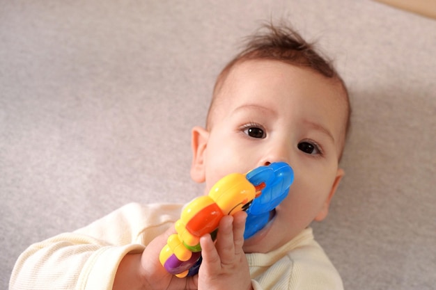 Lindo adorável bebê recém-nascido brincando com chocalho colorido bebê com mordedor retrato adorável de bebê de seis meses em branco com brinquedo de mordedor