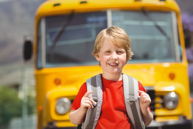 Lindo alumno sonriendo a la cámara en el autobús escolar