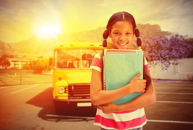 Foto lindo alumno sonriendo a la cámara en la biblioteca contra el autobús escolar amarillo esperando a los alumnos