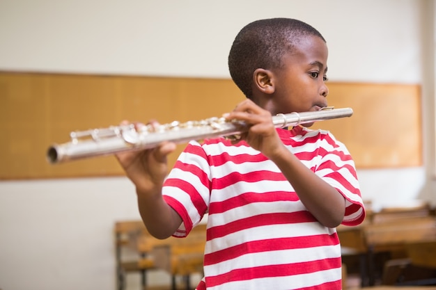 Lindo alumno tocando la flauta en el aula