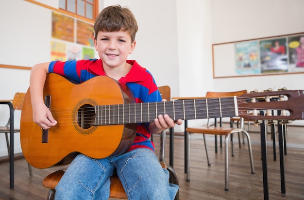 Lindo alumno tocando la guitarra en el aula