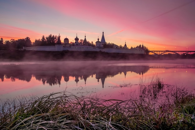 Lindo amanhecer rosa com neblina sobre o rio Catedral da Assunção Rio Volga Staritsa