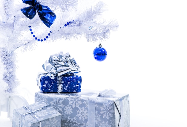 Lindo ano novo apresenta-se na cor azul prata carrinho sob a árvore de Natal em um fundo branco.