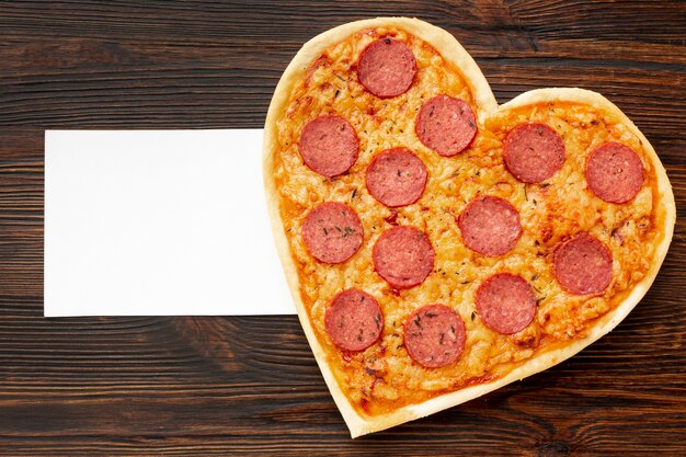 Foto lindo arranjo para o jantar do dia dos namorados com pizza e cartão em forma de coração