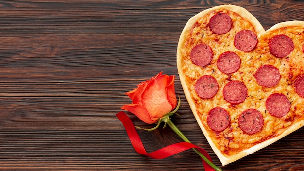Foto lindo arranjo para o jantar do dia dos namorados com pizza em forma de coração e rosa
