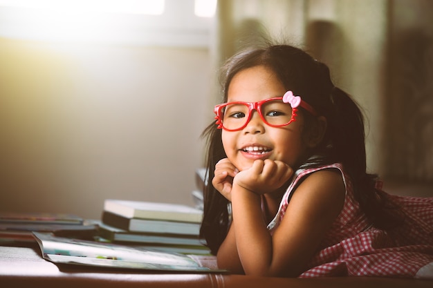 Lindo asiático poco con gafas rojas leyendo un libro. Tono de color de la vendimia