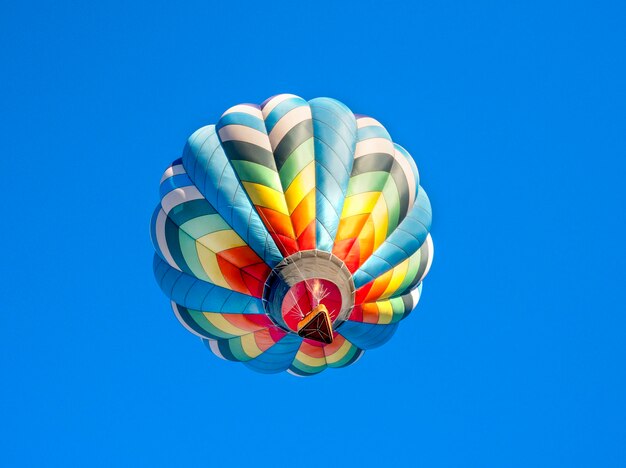 Lindo balão de ar quente colorido voando no céu azul