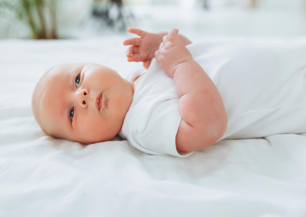 Lindo bebé de 2 meses acostado en la cama ropa de cama natural delicada piel de bebé