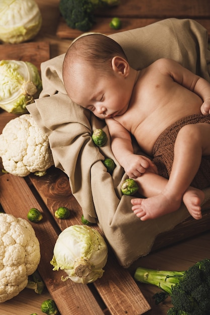 Foto lindo bebé está acostado en la caja con muchas coles diferentes alrededor