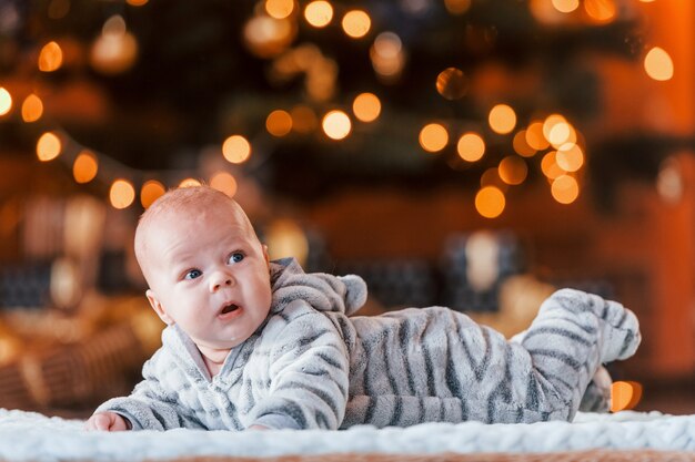 Lindo bebé acostado en la habitación decorada de Navidad.