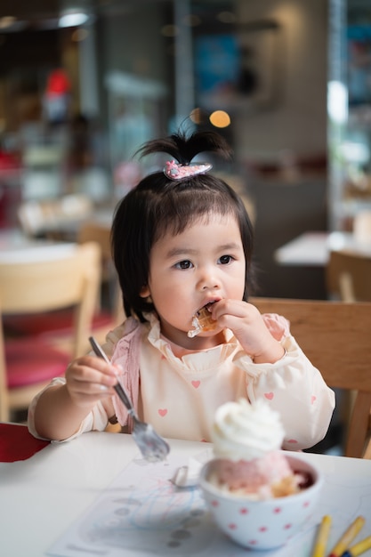 Lindo bebé asiático comiendo helado en la mesa del restaurante