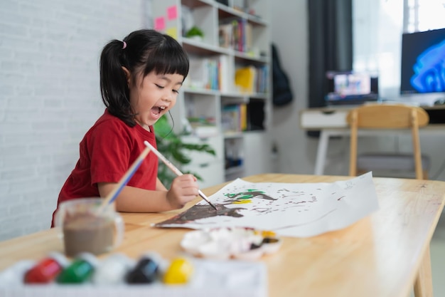 Lindo bebé asiático sonriendo y luagh pintando con pinturas de colores usando acuarela Chica asiática usando pincel de dibujo color Concepto de estilo de vida de actividad de bebé