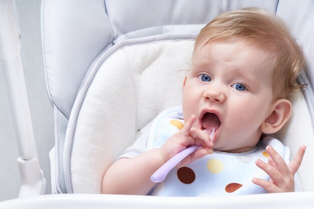 Lindo bebé en un asiento para niños come gachas. Primer señuelo de cerca