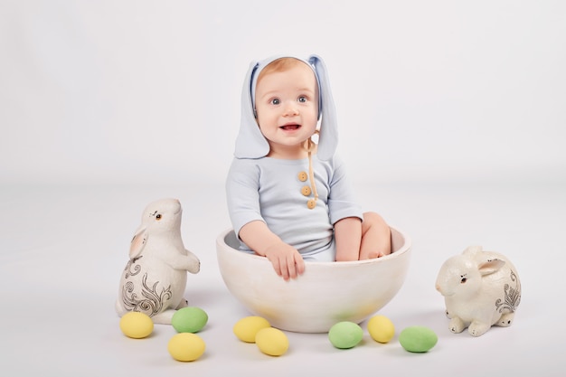 Lindo bebé con conejitos y huevos de Pascua pintados