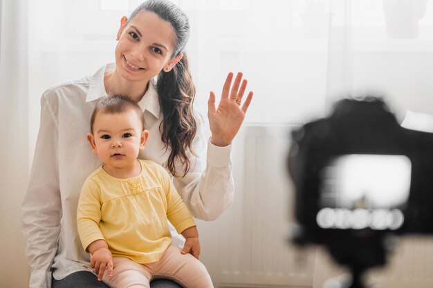 Lindo bebê criança com jovem mãe na frente da câmera vlogging ou blogging