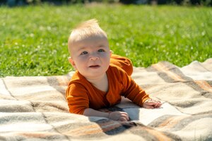 Foto lindo bebê deitado na manta na grama ensolarada