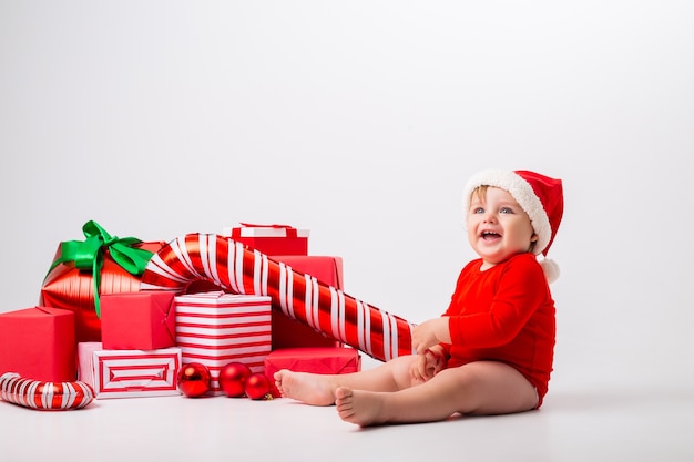 Lindo bebé disfrazado de Navidad con regalos