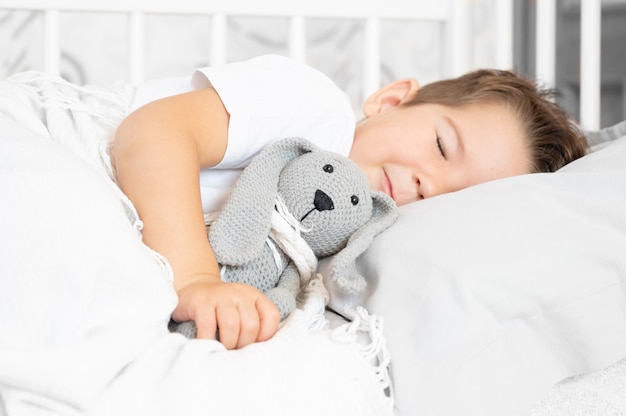 Lindo bebé durmiendo en la cama en casa con juguetes. Foto de alta calidad