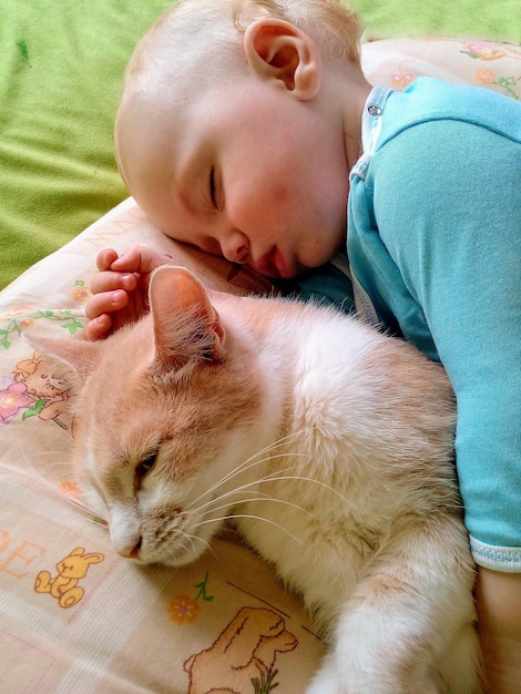 Lindo bebé durmiendo con gato en casa. Hora de acostarse