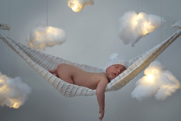 Lindo bebé durmiendo en la hamaca con muchas nubes hechas de algodón.